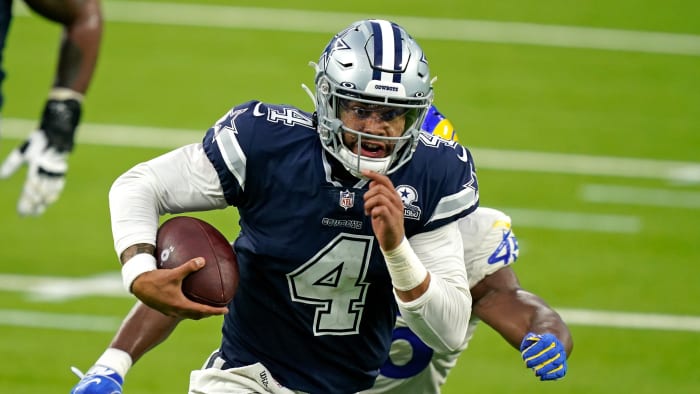Dak Prescott runs from a Rams defender during a game
